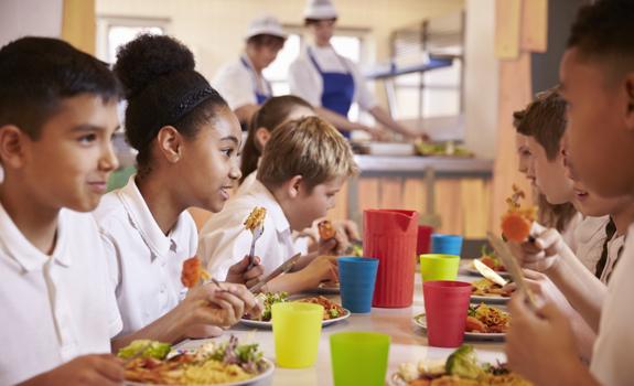 School children enjoying a balanced lunch together, including vegetables and whole foods that contribute to daily fibre intake