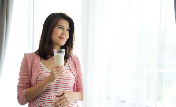 Pregnant woman holding a glass of milk, representing nutritional choices that support health and adequate fibre intake during pregnancy