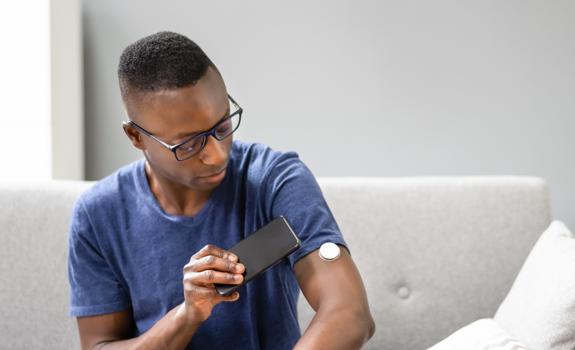 Man checking a glucose sensor on his arm, illustrating monitoring of health as part of a balanced lifestyle that can include fibre-rich nutrition